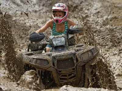 ATV rider off-roading and covered in mud