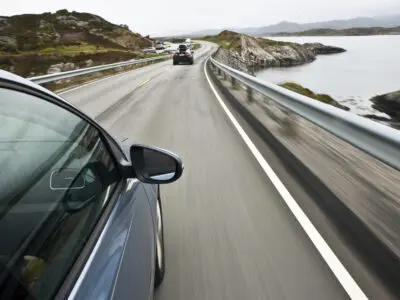 blue car driving down a scenic highway
