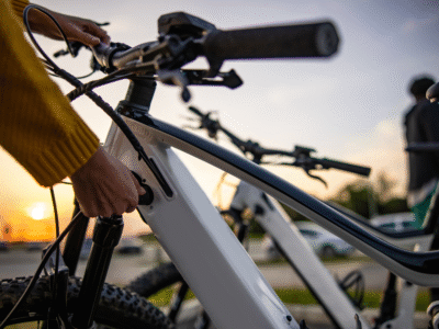 A person plugs in an electric bicycle while the sun sets in the background. The image reflects California’s evolving cycling laws under the OmniBike Bill, which promotes safer road sharing between cyclists and motorists.