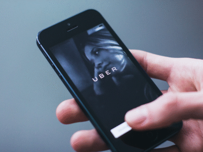 Person holding a smartphone displaying a rideshare app, illustrating legal concerns surrounding Uber’s California ballot initiative and its potential impact on accident victims’ rights and access to personal injury claims.