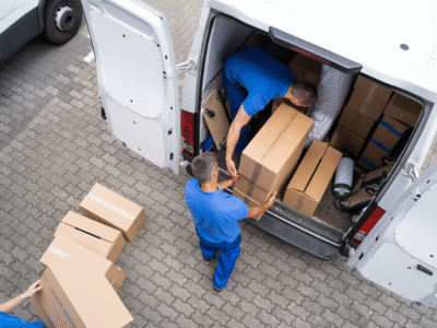 Delivery workers unload packages from a commercial van, illustrating delivery truck operations and potential accident liability in residential areas.