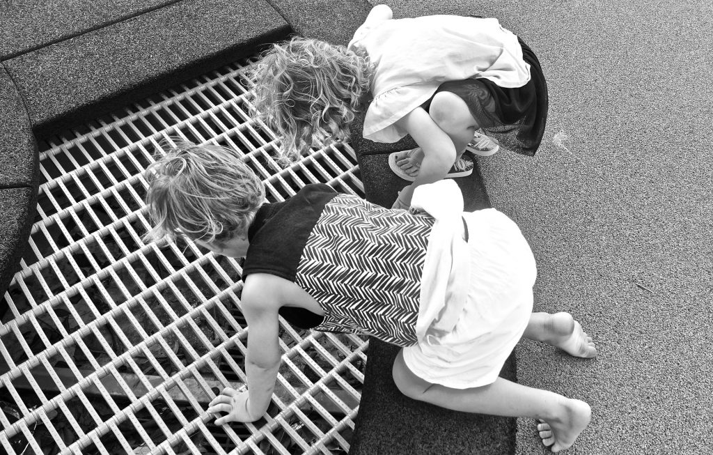 children playing near a sewer grate