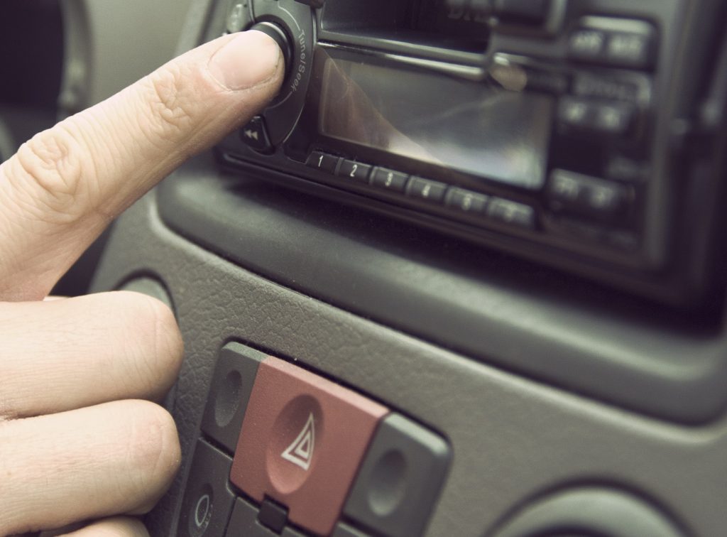 person adjusting the radio volume in a car