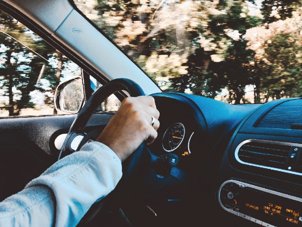 driver with one hand on the steering wheel