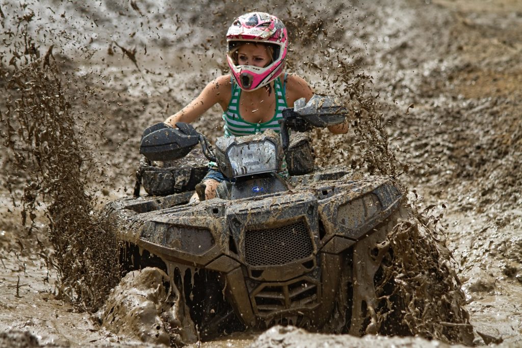ATV rider off-roading and covered in mud