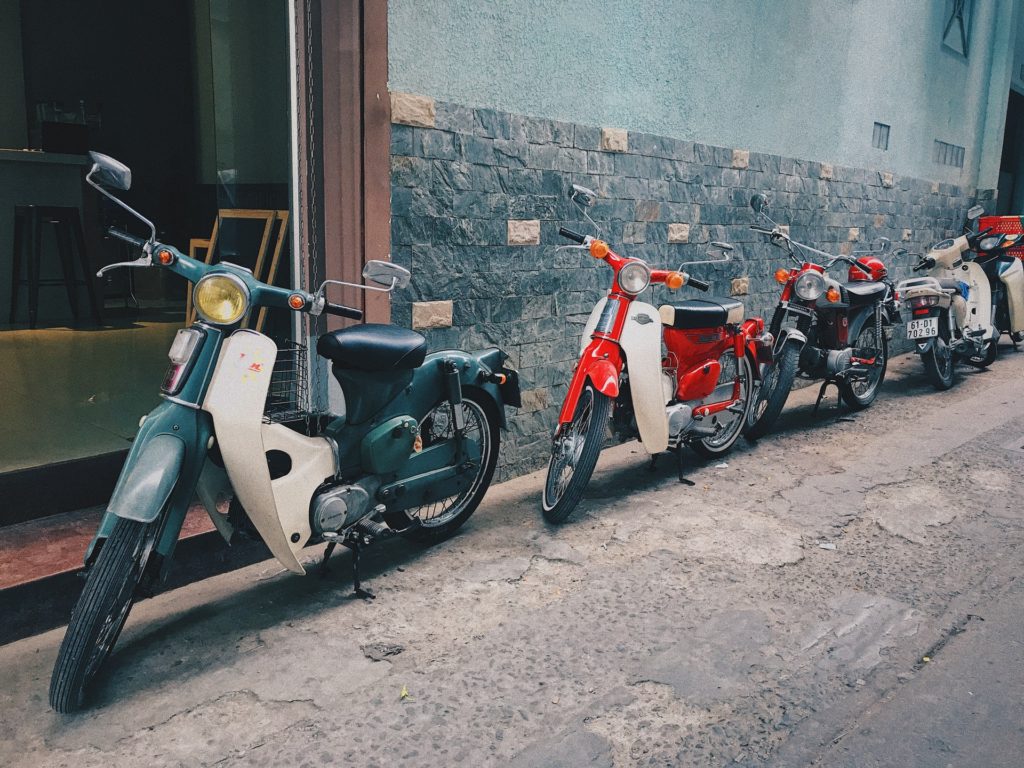 a row of mopeds parked on the side of the street