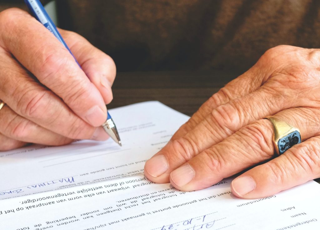 Mans hands signing a document with a pen