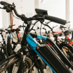 Row of electric bicycles with visible batteries parked indoors, illustrating e-bike use and safety considerations.